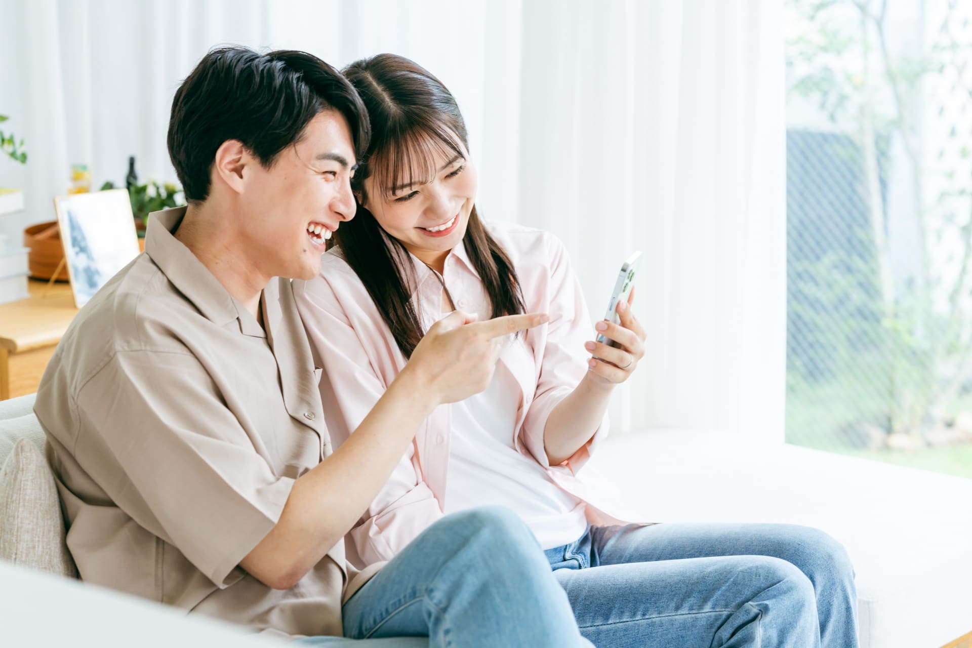 iPhoneを通販で購入するメリットを見ている笑顔の夫婦のイメージ画像
